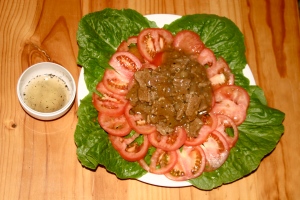Plate over the bed of tomatoes and lettuce. 